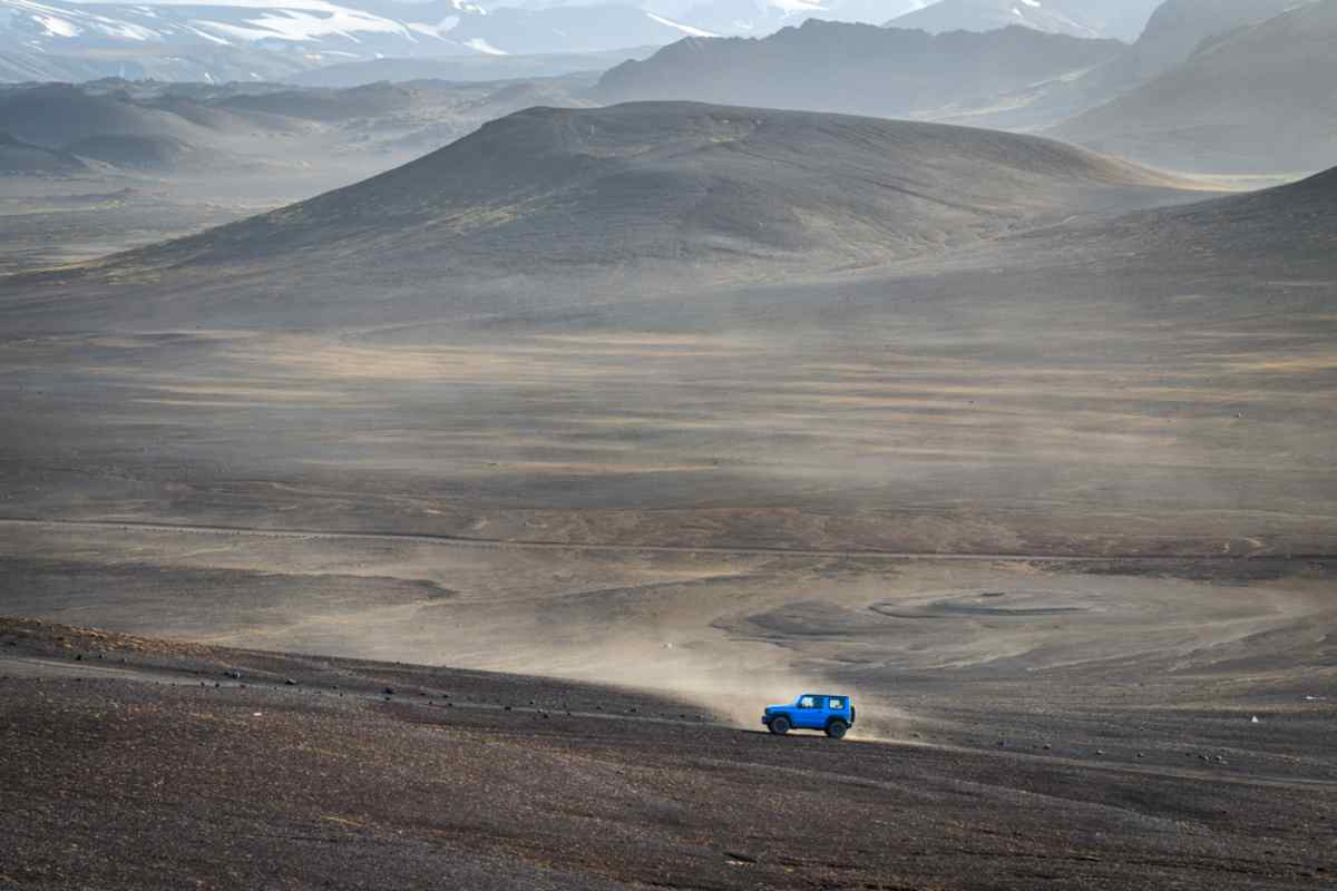 4x4 su piste nere Fuoristrada blu che attraversa un altopiano vulcanico polveroso nelle Highlands islandesi.