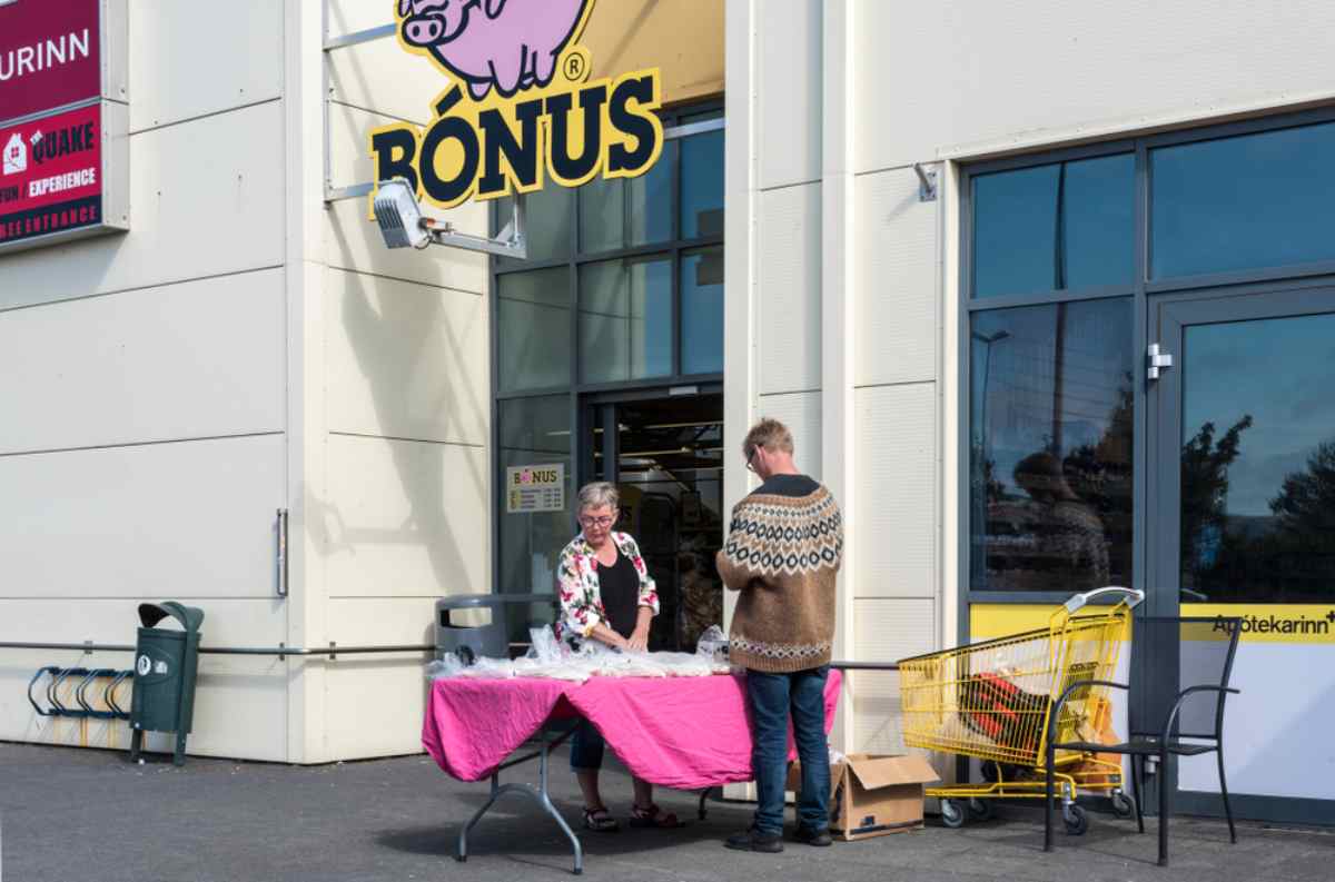 Ingresso del supermercato B&oacute;nus in Islanda con bancarella e carrello giallo.