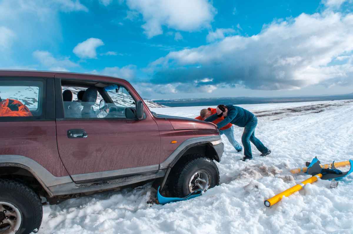 Un veicolo 4x4 bloccato nella neve Un gruppo di uomini cerca di spingere un veicolo 4x4 rimasto bloccato nella neve.