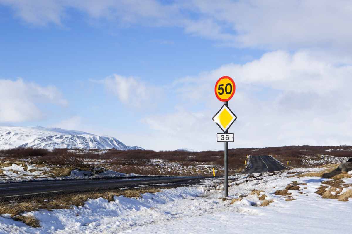 Strada aperta in Islanda con montagne scoscese sullo sfondo e un cartello del limite di velocità